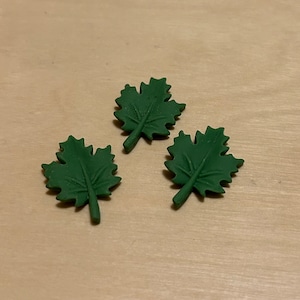 Peut inclure: Trois feuilles d'érable en feutre vert avec une texture en relief.