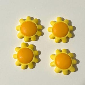 May include: Four yellow sun-shaped buttons with orange centers.