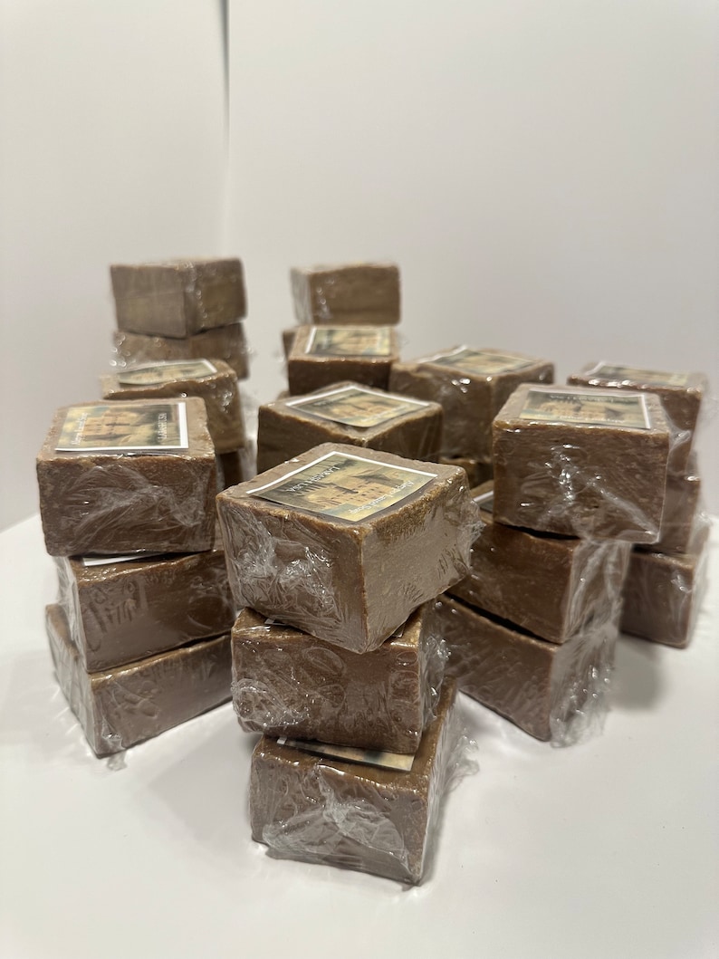 Puede incluir: Una pila de barras de jab&oacute;n marrones envueltas en pl&aacute;stico transparente. Las barras de jab&oacute;n tienen una etiqueta con un dise&ntilde;o de un &aacute;rbol y el texto "African Black Soap".
