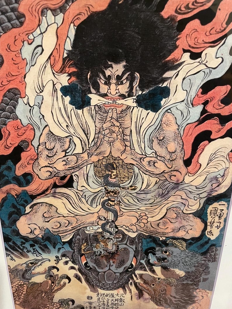 May include: A detailed Japanese woodblock print featuring a seated figure with a stern expression, dark hair, and a white robe. The artwork includes a snake, a turtle, and various mythical creatures, with red, blue, and gold accents.