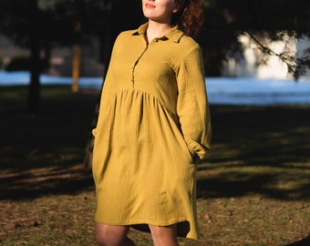 Puede incluir: Vestido mostaza de manga larga con cuello y abotonadura. El vestido presenta una cintura fruncida y bolsillos. La tela tiene un aspecto texturizado. El vestido llega a la rodilla.