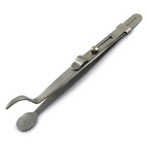 May include: A stainless steel tweezer with a locking mechanism and a curved tip. The tweezer has a textured grip and a small, round, textured pad at the end of the curved tip.