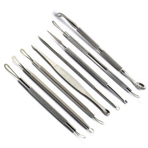 May include: An assortment of stainless steel skincare tools, including loop extractors, lancets, and a comedone extractor. The tools have textured handles for grip and are arranged diagonally against a white background. These tools are designed for facial blemish removal.
