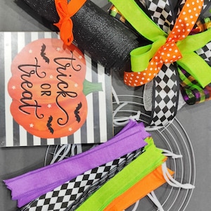 May include: Halloween wreath making kit with black mesh, orange and white polka dot ribbon, black and white checkered ribbon, green ribbon, purple, green, orange and black and white checkered ribbon, a metal wreath form, and a sign that says "Trick or Treat".