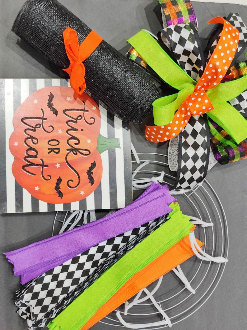 May include: Halloween wreath making kit with black mesh, orange and white polka dot ribbon, black and white checkered ribbon, green ribbon, purple, green, orange and black and white checkered ribbon, a metal wreath form, and a sign that says "Trick or Treat".