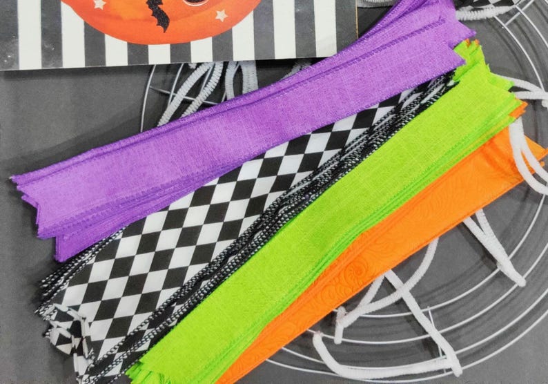 May include: A set of Halloween craft supplies including purple, green, and orange ribbon, black and white checkered ribbon, and white pipe cleaners.