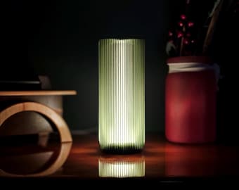 May include: A green glass table lamp with a ribbed design. The lamp is turned on and illuminating the room.