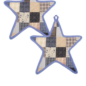 May include: Two star-shaped quilted pot holders. Each pot holder is made of patchwork fabric in shades of beige, blue, and brown, with a light blue border and hanging loop. The pot holders are designed for kitchen use.