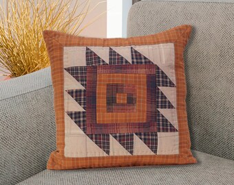Puede incluir: Una almohada de patchwork marrón y crema con un diseño geométrico. La almohada está hecha de diferentes telas y tiene una textura acolchada.