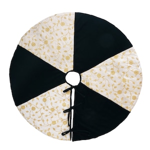May include: A black and white Christmas tree skirt with a gold floral pattern. The skirt has a tie closure in the center.
