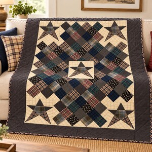 Op de afbeelding: Een doorgestikte plaid met een patchworkontwerp van marineblauwe, antracietkleurige en crèmekleurige stoffen vierkanten. Het patroon bevat vijf donkere ruitvormige sterren, één in het midden en vier in de hoeken, omlijst door een antracietkleurige rand.