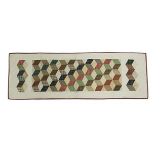 May include: A rectangular quilted table runner with a repeating geometric pattern of 3D cubes in various colors, including red, green, brown, and cream. The runner has a cream-colored border with a brown trim.