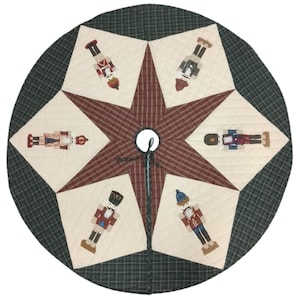 May include: Circular Christmas tree skirt with a starburst design. The center star is burgundy plaid, surrounded by cream-colored panels with embroidered nutcracker figures. The outer border is green plaid.