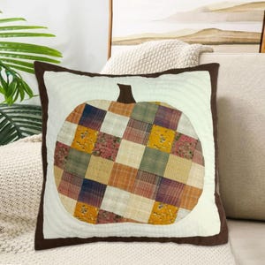 May include: A brown and white patchwork pumpkin cushion with a brown border. The cushion is made of various fabrics with different patterns, including plaid, floral, and geometric designs.