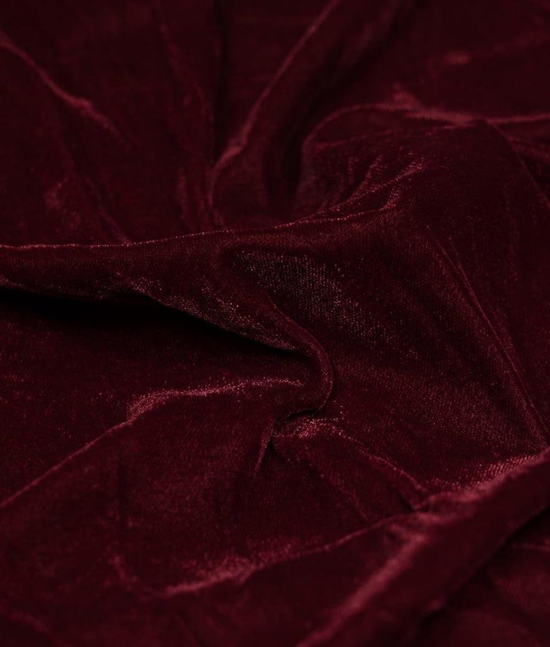 May include: Close-up of a deep red velvet fabric with a soft, plush texture. The fabric is draped and folded, creating a luxurious and elegant look.