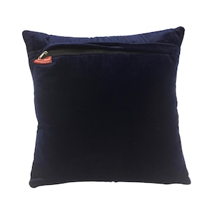 May include: A dark blue velvet pillow with a zipper closure on the back. The zipper pull is red.