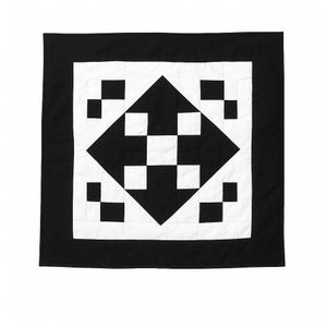 May include: Black and white quilt with a diamond pattern in the centre. The diamond is made up of smaller squares, alternating in colour. The quilt is surrounded by a black border.