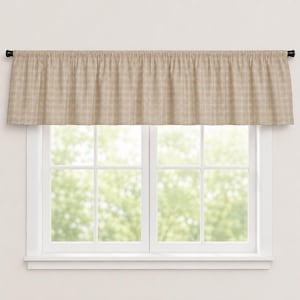 Puede incluir: Una cenefa a cuadros beige sobre una ventana blanca. La cenefa está hecha de una tela tejida con un sutil patrón de cuadros en tonos beige y crema. La ventana tiene una rejilla de cristales y el fondo muestra una vista borrosa de follaje verde.