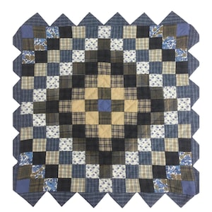 May include: A blue and brown patchwork quilt with a scalloped edge. The quilt is made of squares of different fabrics, including plaid, floral, and solid colors.