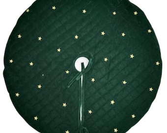 Puede incluir: Una falda redonda para árbol de Navidad, de color verde oscuro, con un diseño acolchado y estrellas doradas bordadas. La falda tiene una abertura central con cierre de lazo. El diseño es festivo y decorativo.