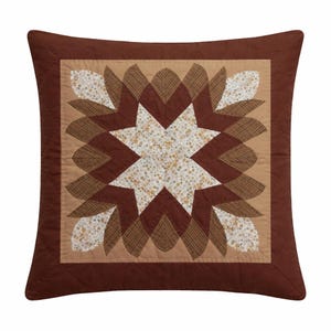 Peut inclure: Coussin carré décoratif avec un motif d'éclat d'étoile matelassé. Le coussin présente un motif d'étoile central en tissu floral blanc, entouré d'éléments en forme de pétales marron et beige. La bordure extérieure est marron foncé uni.