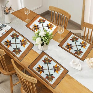 Può includere: Un tavolo da pranzo in legno con quattro tovagliette decorative e un runner da tavolo. Le tovagliette e il runner presentano un motivo floreale geometrico nei toni del marrone, arancione e verde. Il tavolo è apparecchiato con bicchieri e composizioni floreali.