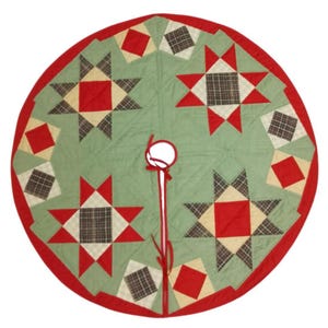 May include: A round Christmas tree skirt with a green center, red border, and star and diamond patchwork design. The patchwork includes red, cream, and plaid squares. A white circle and red ribbon are at the center.