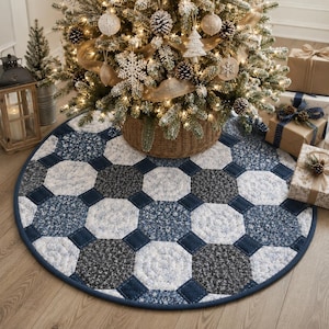 May include: A round Christmas tree skirt with a patchwork design in shades of blue and white. The skirt features a dark blue border and a geometric pattern, creating a festive base for a decorated tree.