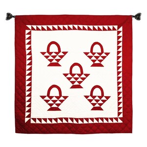May include: A red and white quilt with a pattern of baskets. The baskets are made of white triangles and are surrounded by a red border. The quilt has a red border with a white triangle pattern.