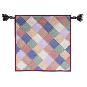 May include: A colorful patchwork quilt wall hanging with a burgundy border and black butterfly finials. The quilt is made of squares of various shades of pink, blue, green, and beige.
