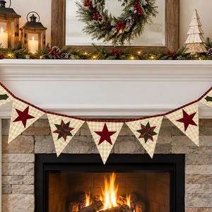 May include: A decorative fabric bunting banner featuring triangular pennants with a cream and tan checkered pattern. The pennants are adorned with alternating dark red stars and green holly leaf motifs, all connected by a dark red plaid fabric trim.
