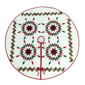 May include: A round, white Christmas tree skirt with a red border and a central opening. The skirt features a star pattern in red, green, and brown, with a zigzag border design. A red ribbon is attached to the opening.