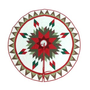 May include: Circular Christmas tree skirt with a starburst design. The skirt features a white background with a central red star, accented by green, brown, and red geometric shapes. The edge is trimmed with a red border and brown triangles.