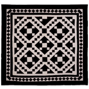 May include: Black and white quilt with a geometric pattern of diamonds and squares. The quilt is framed with a black border with a diamond pattern.