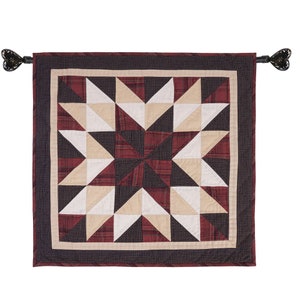 May include: A red, white, and black quilted wall hanging with a starburst design. The hanging has a black border and is attached to a black rod with decorative finials.