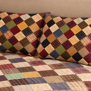 Peut inclure: Deux coussins carrés avec un motif patchwork dans diverses couleurs, dont le rouge, le bleu, le vert et le jaune. Les coussins reposent sur une courtepointe patchwork assortie, créant une esthétique cohérente et chaleureuse.