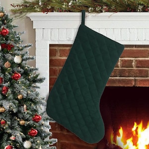 May include: A dark green quilted Christmas stocking hanging on a white mantel above a fireplace.