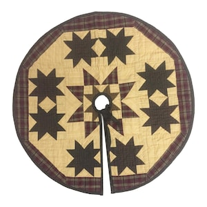 May include: A beige quilted Christmas tree skirt with a brown and red plaid border. The skirt features a starburst pattern with brown stars on a beige background.
