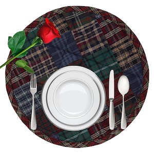 May include: A round plaid placemat with a red rose, a white plate, a fork, a knife, and a spoon.