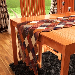 May include: A patchwork table runner with a mix of red, brown, orange, and white squares. The runner is on a wooden table with two chairs.