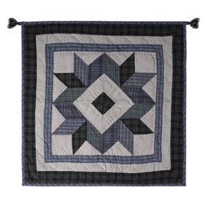 May include: A blue and black quilted wall hanging with a starburst pattern. The wall hanging has a fringe border and is made of patchwork fabric.