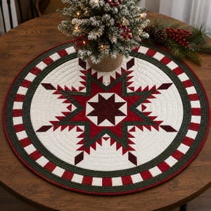 Peut inclure: Un tapis de table rond matelassé présentant une étoile centrale à huit branches dans des tons rouge foncé et vert forêt sur fond blanc. La bordure se compose de carrés alternés rouges et blancs encadrés par une bande vert foncé piquée.