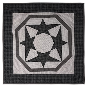 May include: A black and white quilt with a large eight-pointed star in the center. The star is made up of smaller squares and rectangles, and the quilt is edged with a black border.