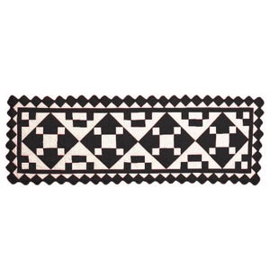 May include: Black and white quilt runner with a geometric pattern of squares and diamonds. The runner has a scalloped edge.
