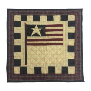 May include: A quilted throw pillow with a red, white, and blue American flag design in the center. The pillow has a black and white checkered border and a red, green, and black plaid outer border.