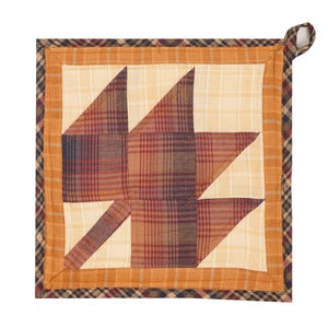 May include: A quilted pot holder with a brown, orange and cream plaid pattern. The pot holder is shaped like a maple leaf and has a loop for hanging.