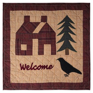 Pode incluir: Uma tapeçaria de parede acolchoada com um design rústico. Apresenta uma casa, um pinheiro e um corvo preto. A palavra "Welcome" é bordada em bordô. O fundo é bege com uma borda bordô.
