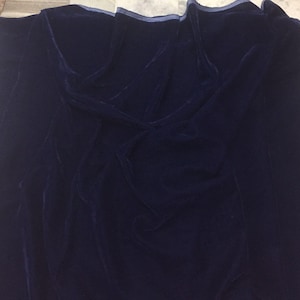May include: A dark blue velvet fabric with a subtle sheen. The fabric is folded and draped, showcasing its texture.