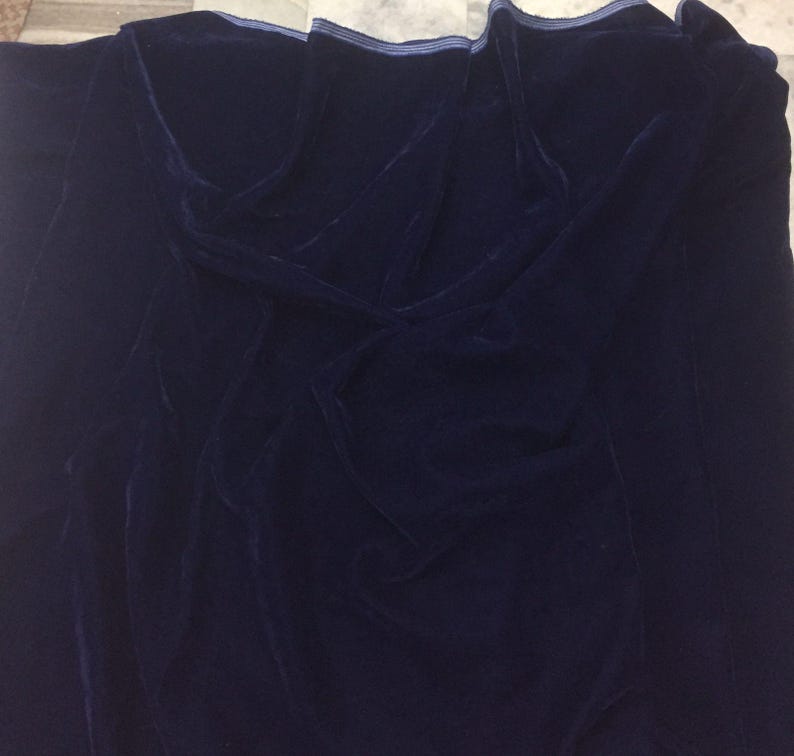 May include: A dark blue velvet fabric with a subtle sheen. The fabric is folded and draped, showcasing its texture.