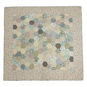 May include: A handmade quilt with a floral pattern and a hexagon design. The quilt features a variety of pastel colors, including pink, blue, and green, with a cream-colored background. The border is a cream color with small red flowers.